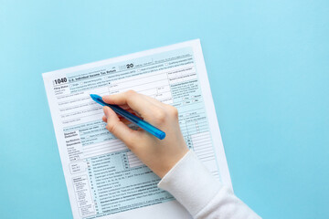 The hand writes with a pen on the 1040 tax form. 1040 Individual Income Tax Return. With copy space, space for text 