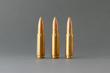 Three bullets on gray background. Cartridges 7.62 caliber for Kalashnikov assault rifle closeup