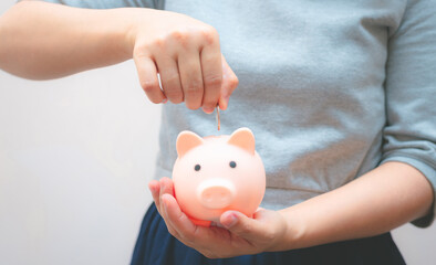 business woman hold piggy bank and putting coin with concrete wall for financial and saving money...