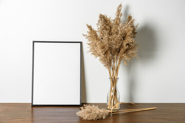 Dry reeds pampas grass in vase with black photo or poster frame, mock up