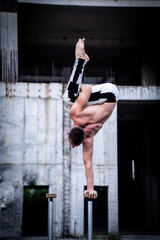 Man keeps balance on one hand on the concrete structure background. Concept of yoga, meditation and healthy lifestyle