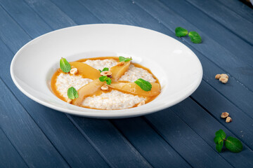 Oatmeal milk porridge with pear and caramel syrup on a blue wooden table. Healthy eating, healthy food