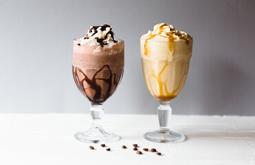 Chocolate and coffee and vanilla milkshakes on a white surface and grey background
