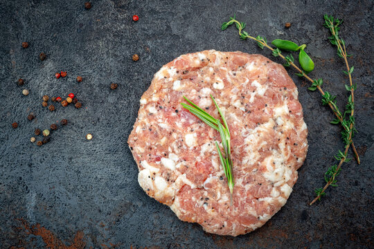 Fresh raw minced meat or pork cutlets on stone with seasonings, top view