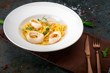 Asian-style seafood pasta. Plate of spaghetti with squid, pepper and hot tom yam sauce