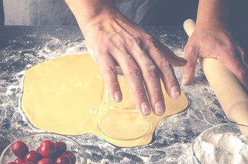 closeup of a young caucasian man kneading a piece of dough to prepare a coca de cireres, a cherry...