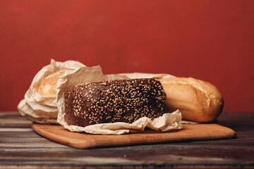 loaf of bread flour product on a tray on a wooden table and red background, pastries