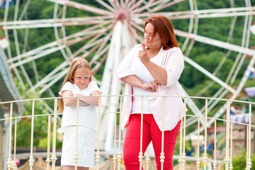 Family. The mother shakes her finger at her daughter for her capricious behavior. Ferris wheel in the background. Concept of family holidays and education