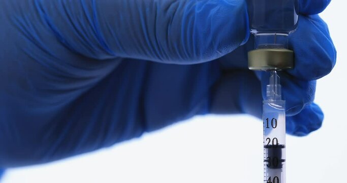 Medical nurse hand in safety gloves holds a syringe and vaccine bottle. Doctor uses hypodermic needle and a syringe to put a shot of drug as treatment. Health and medical concepts. Clinic hospital.