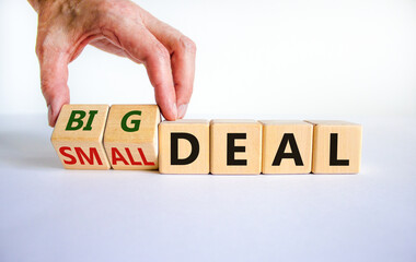 Big or small deal symbol. Businessman turns a wooden cube and changes words 'small deal' to 'big deal'. Beautiful white table, white background, copy space. Business and big or small deal concept.