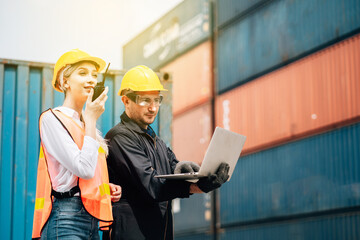 workers teamwork man and woman in safety jumpsuit workwear with yellow hardhat and use laptop check container at cargo shipping warehouse. transportation import,export logistic industrial service