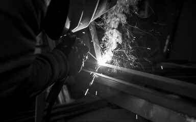 Close-up of a place where a welder welds two pipes. It is located in the workshop and the smoke...
