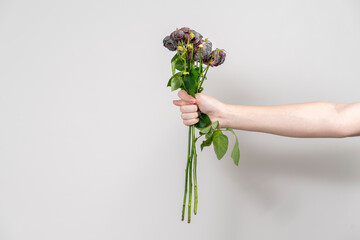 the man's hand holds out a bouquet of wilted flowers and shows a fig