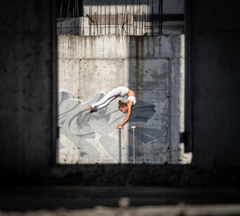 Flexible and fit girl standing on her hands keeping balance in the abandoned building. Concept of effort and healthy lifestyle 