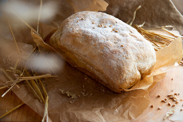 Freshly baked rye bread on a wooden board. Burlap, wheat ,craft paper and straw on the background. Organic bread baked at home from wheat flour.