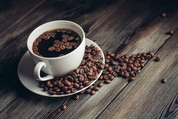 saucer with coffee beans and white cup on a wooden table side view Copy Space