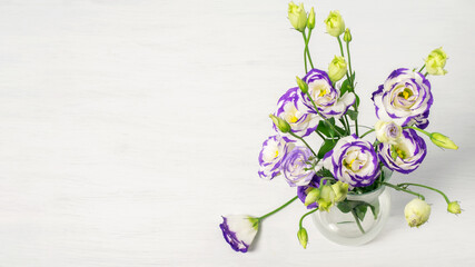 Lisianthus blu flowers bouquet in glass vase. Greeting card design for Mother's day, Women's day or Valentine's day. Top view, banner photo with space for your text.