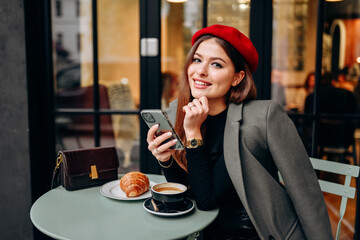 Female blogger chatting with followers in social networks on modern smartphone using 5G internet connection.Hipster girl in watching video on website on cellular in cafe.
