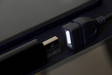 A USB flash drive and an OTG adapter lie on a black background next to gadgets - smartphones or...