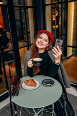 Female blogger chatting with followers in social networks on modern smartphone using 5G internet connection.Hipster girl in watching video on website on cellular in cafe.