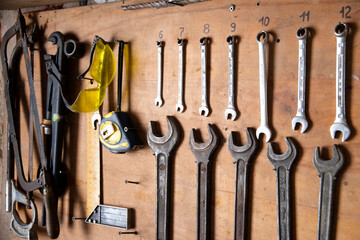 Wood wall with tools.Old tools hanging on the wall in the garage. Equipment concept - work tools hanging on wall at workshop. Wrenches.