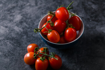 fresh tasty cherry tomatoes on dark stone background with copy space