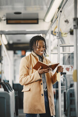 African American man riding in the city bus. Guy in a brown coat. Man with notebook.