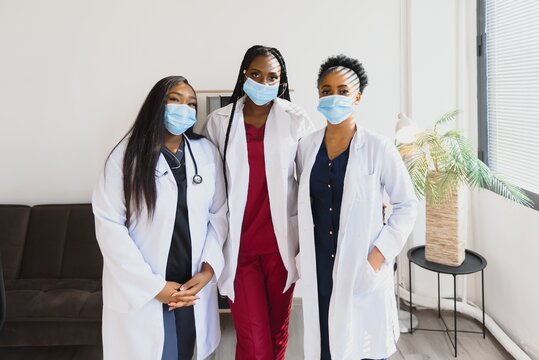 Group Of Healthcare Workers Wearing Protective Face Masks While Standing With Arms Crossed And Looking At Camera.