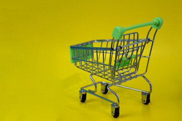 Shopping cart empty on yellow background, supermarket shopping concept. Place for an inscription. The concept of food prices in a supermarket, holiday discounts.