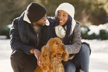 People walks outside. Winter day. African couple with dog.