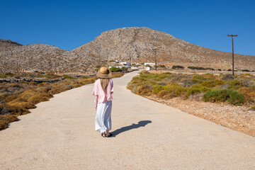 Folegandros, Greece - September 25, 2020: A tourist woman standing on the road in the southern coast of the island of Folegandros. Cyclades, Greece
