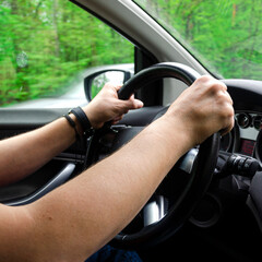 Men's hands hold the steering wheel while traveling. Driving a car