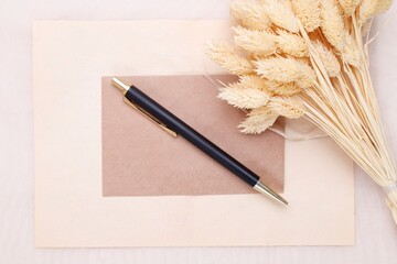 Czarno złoty długopis na beżowej kartce i suszone kwiaty  - obrazy, fototapety, plakaty