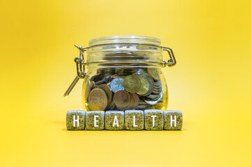 Health text on cubes with A lot coins in glass money jar. Investment and Saving Concepts.