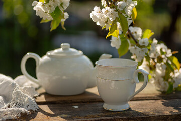 Tea set, cherry blossom branches, wooden table. Outdoor breakfast, picnic, brunch, spring mood. Soft focus