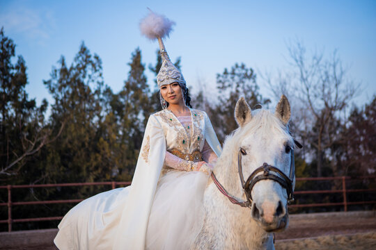 An Asian girl in a national costume is riding a horse. Kyrgyz national costume.