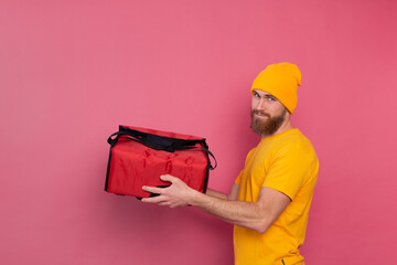 European bearded delivery man with box with food  pink background isolated