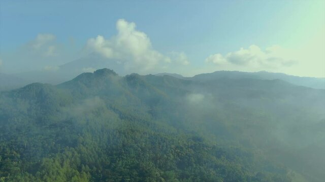 Aerial panorama Menoreh hills overgrown with tropical forest seen though clouds