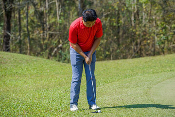 Golfer putting ball on the green golf, lens flare on sun set evening time. Golfer action to win after long putting golf ball in to the hole.