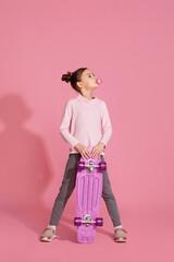 cool little child girl with chewing gum holding skateboard