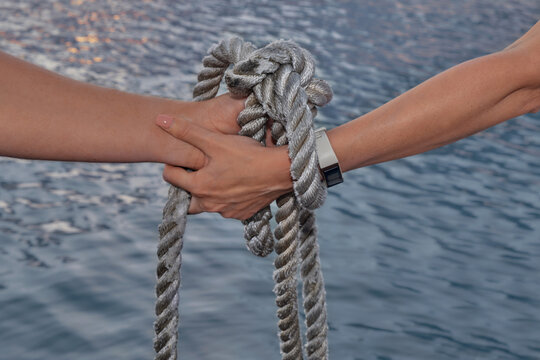 Wedding ceremony handsbye, wedding anniversary, valentine's day tied in nautical rope handfasting vows, as a sign of eternal love and veneration. Young hands are tied with a carrot with a rope as a