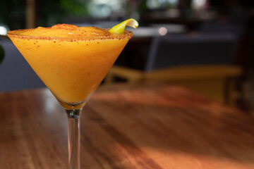 Mango margarita frappe on wooden table. Mango daiquiri on sunny day, sunny weather. Daisy in summer.