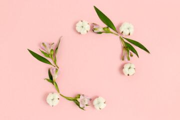 Fototapeta premium Square frame made of alstroemeria flowers, cotton and green leaves on a pink pastel background. Holiday floral composition.