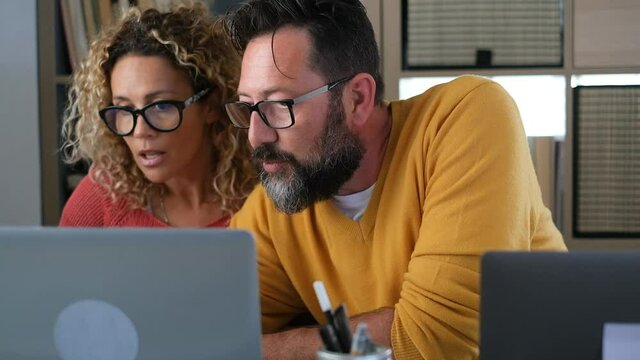 Young adult man and woman working at home with computer laptop and online internet connection - concept of free office smart working lifestyle and happy people team - couple in video call conference