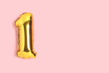 Number 1 golden balloon with copyspace. One year anniversary celebration concept on a pink background.