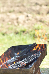 defocused orange flame of a campfire for barbecue in summer on green grass background