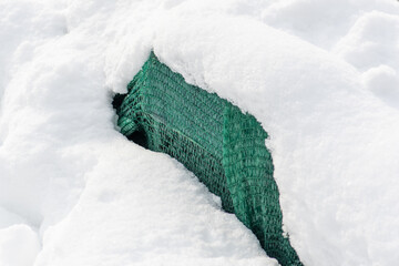 Plants and trees in a park or garden covered by the snow and blanket, swath of burlap, frost protection bags or roll of fabric to protect them from frost, freeze and cold temperature