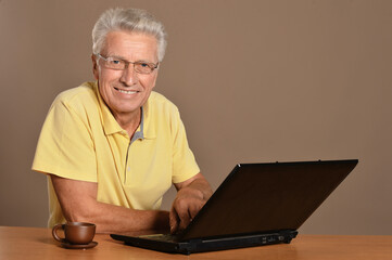 Smiling senior man sitting at table with laptop