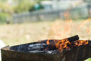 defocused orange flame of a campfire for barbecue in summer on green grass background