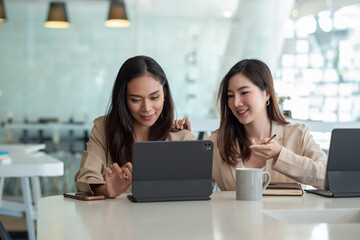 Two Asian beautiful woman consult a collaboration structure using a tablet at the office.